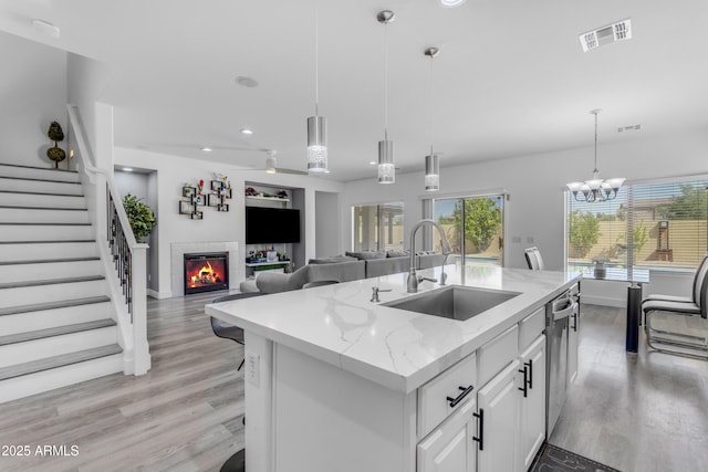 kitchen with light wood-style floors, a fireplace, a sink, and visible vents