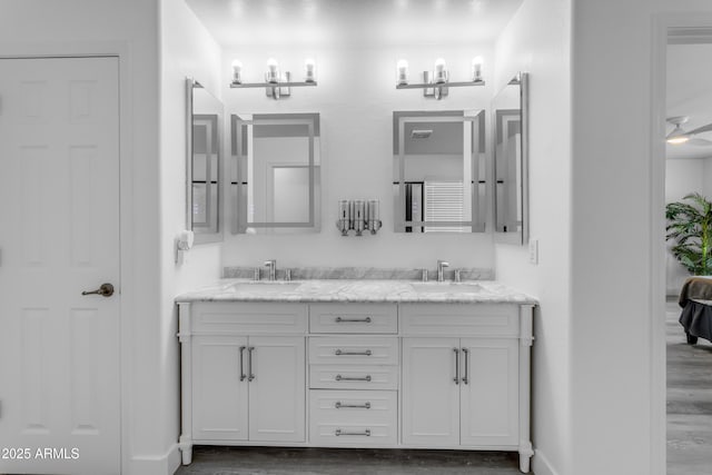 full bath with double vanity, a sink, and wood finished floors