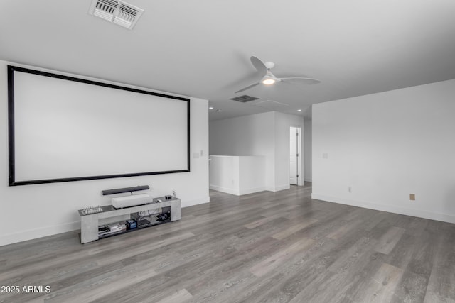 home theater room with wood finished floors, baseboards, a ceiling fan, and visible vents