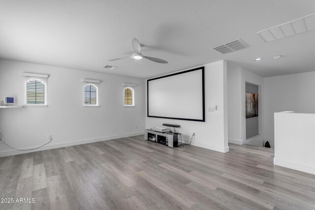 home theater with wood finished floors, baseboards, a ceiling fan, and visible vents