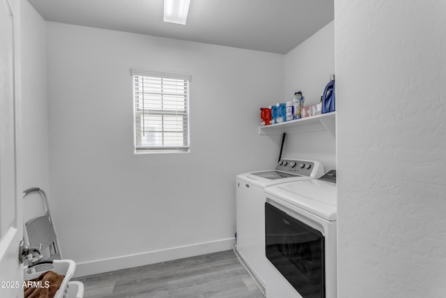 clothes washing area featuring light wood finished floors, laundry area, washing machine and clothes dryer, and baseboards