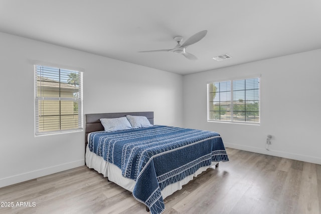 bedroom featuring visible vents, multiple windows, baseboards, and light wood-style flooring