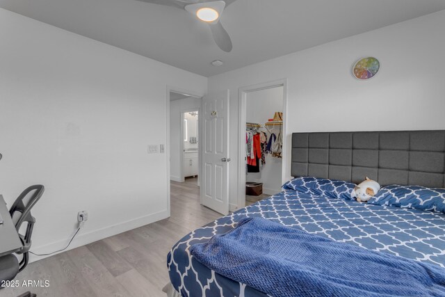 bedroom with ceiling fan, a closet, a spacious closet, wood finished floors, and baseboards