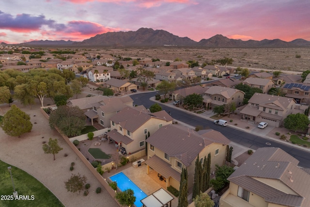 aerial view at dusk featuring a mountain view and a residential view