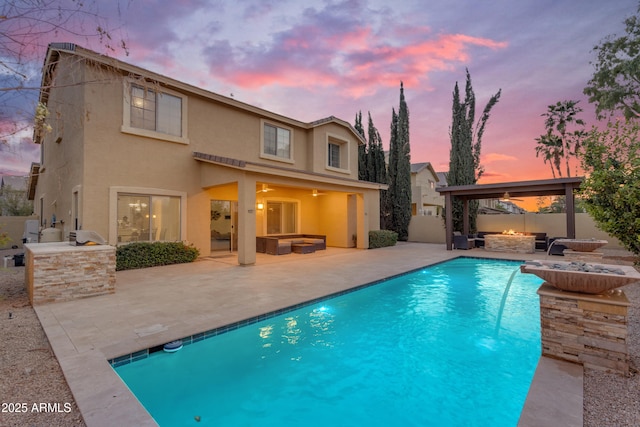 back of house with fence, stucco siding, a patio, and an outdoor kitchen