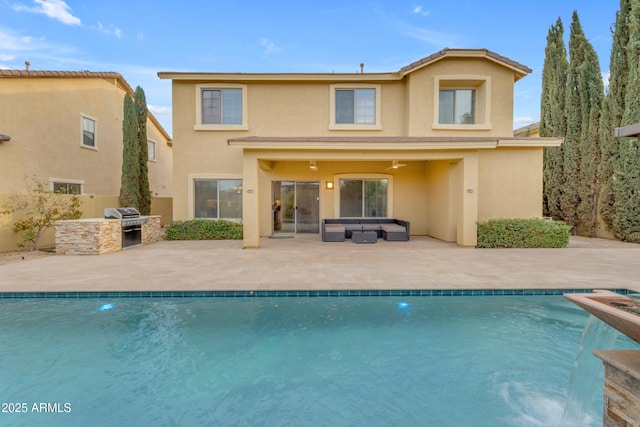 rear view of property featuring a patio area, exterior kitchen, an outdoor hangout area, stucco siding, and an outdoor pool