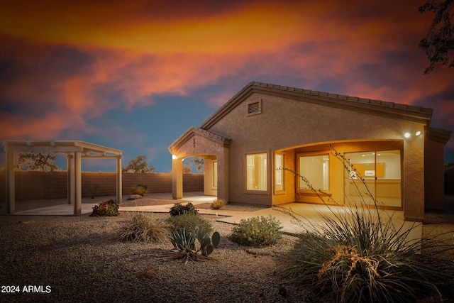 back house at dusk featuring a patio area and a pergola