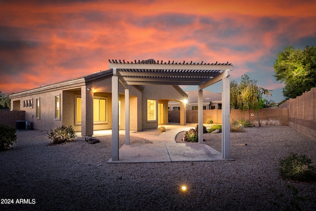 back house at dusk featuring a patio area, central AC, and a pergola