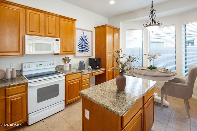 kitchen with hanging light fixtures, light stone counters, light tile patterned flooring, a center island, and white appliances