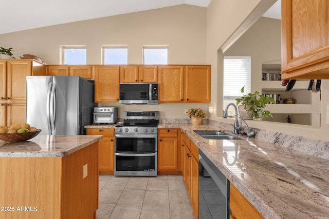 kitchen with lofted ceiling, sink, light tile patterned floors, appliances with stainless steel finishes, and light stone countertops