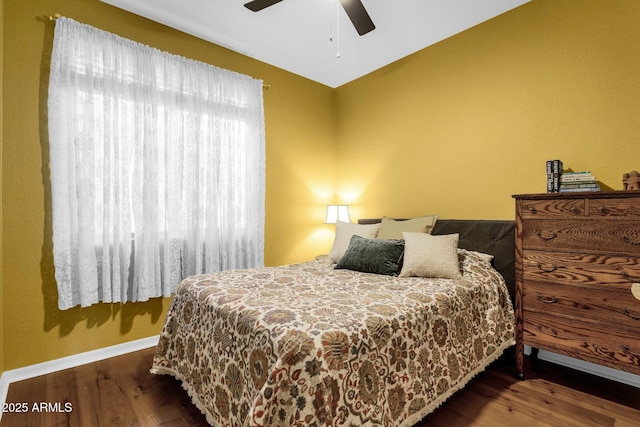 bedroom with dark hardwood / wood-style flooring, vaulted ceiling, and ceiling fan