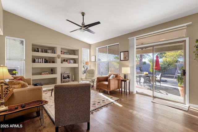 living area featuring ceiling fan, built in features, lofted ceiling, and light hardwood / wood-style flooring