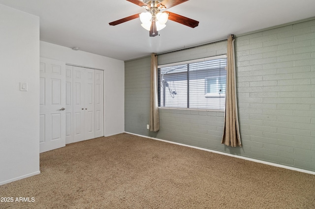 unfurnished bedroom with ceiling fan, brick wall, carpet flooring, and a closet