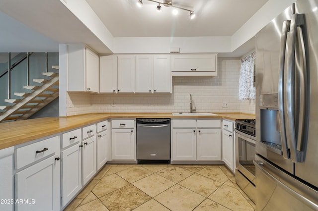 kitchen with wood counters, sink, white cabinetry, appliances with stainless steel finishes, and decorative backsplash