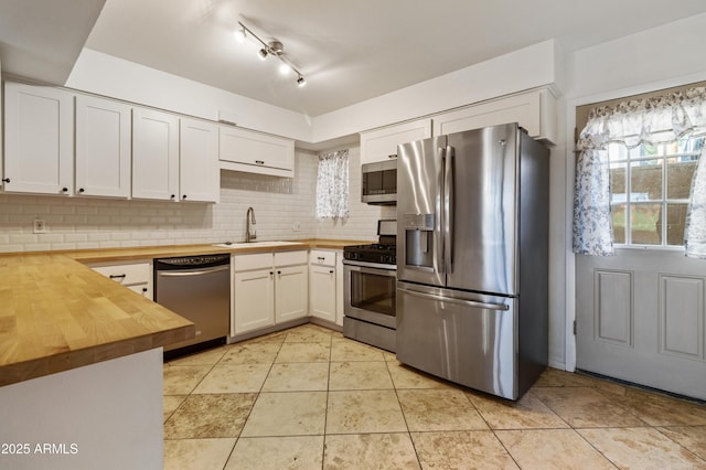 kitchen featuring sink, white cabinetry, backsplash, butcher block counters, and stainless steel appliances