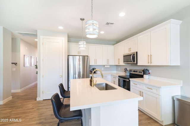 kitchen featuring stainless steel appliances, sink, pendant lighting, and white cabinets