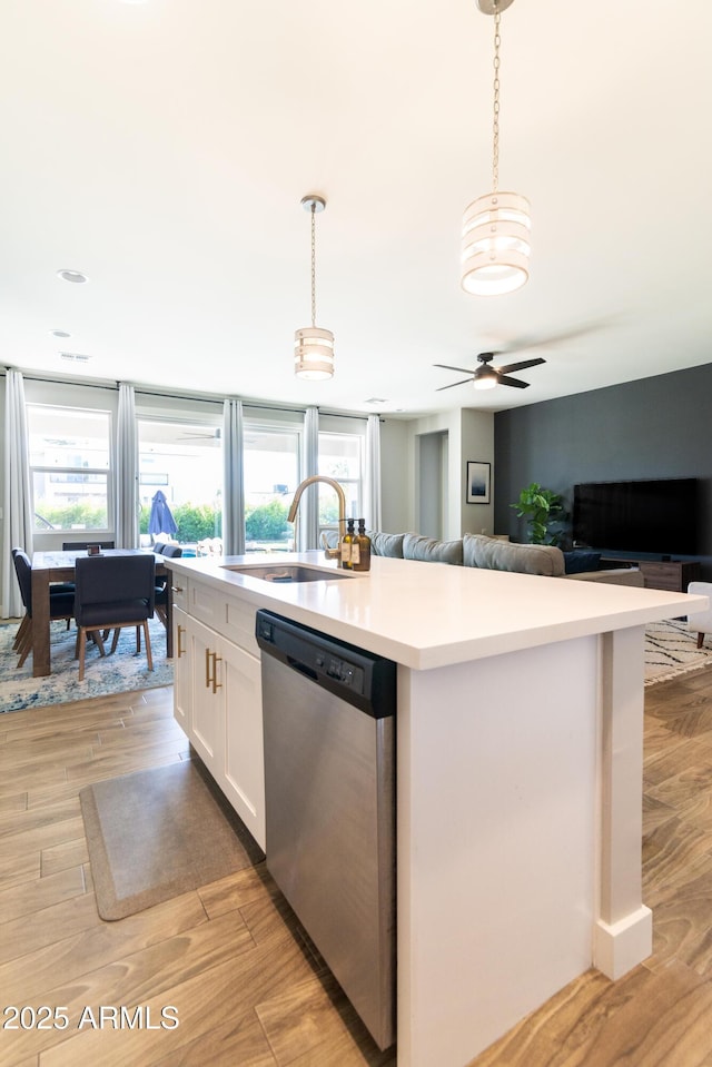 kitchen with decorative light fixtures, sink, white cabinets, a kitchen island with sink, and stainless steel dishwasher