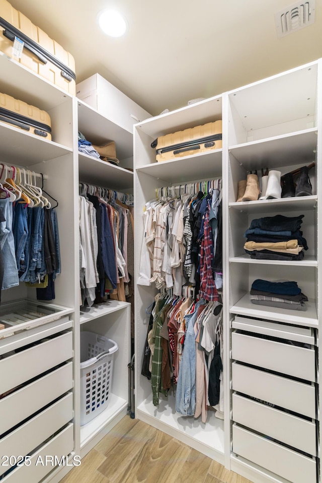 walk in closet with light hardwood / wood-style flooring