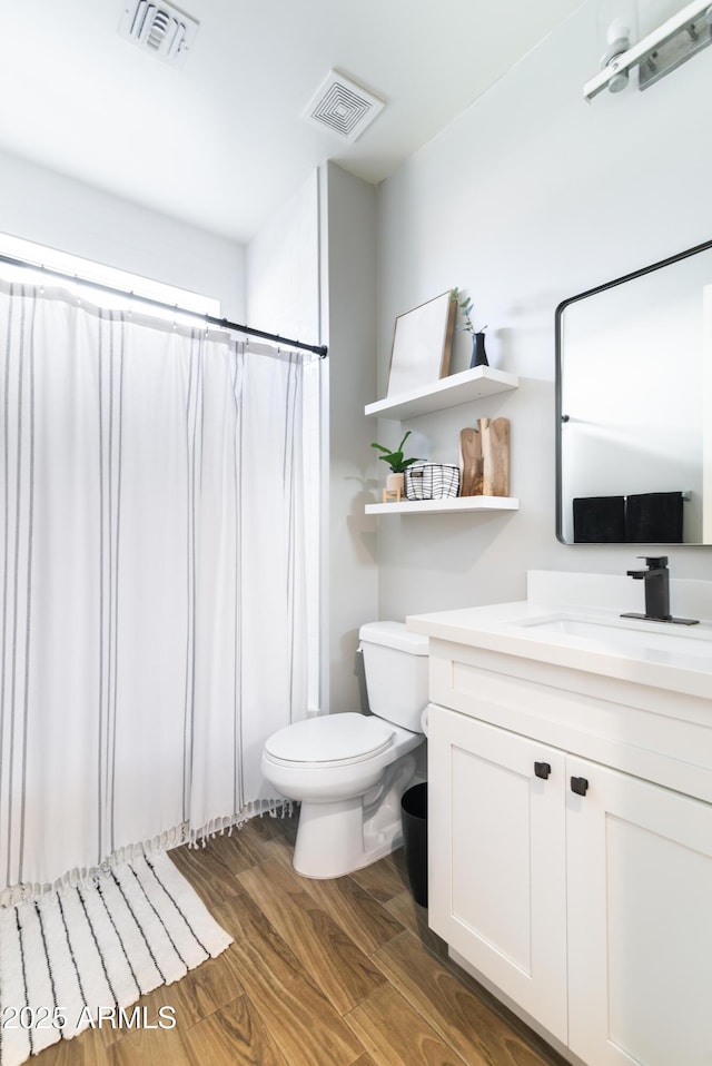 bathroom featuring hardwood / wood-style flooring, vanity, walk in shower, and toilet