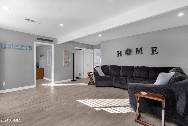 living room featuring beamed ceiling and light hardwood / wood-style floors