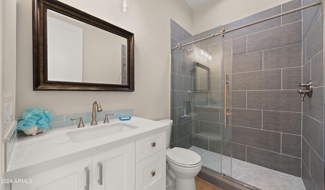 bathroom featuring vanity, toilet, and a shower with shower door