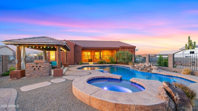 pool at dusk featuring an in ground hot tub, a patio, and a gazebo