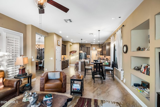 tiled living room with ceiling fan with notable chandelier