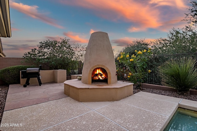 patio terrace at dusk with an outdoor fireplace