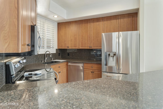 kitchen with tasteful backsplash, appliances with stainless steel finishes, sink, and dark stone countertops