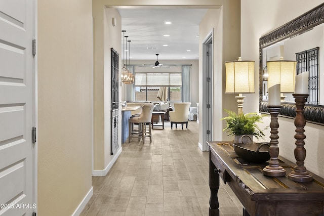 corridor featuring baseboards, wood finished floors, and recessed lighting