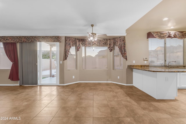 unfurnished dining area featuring ceiling fan, light tile patterned flooring, and sink