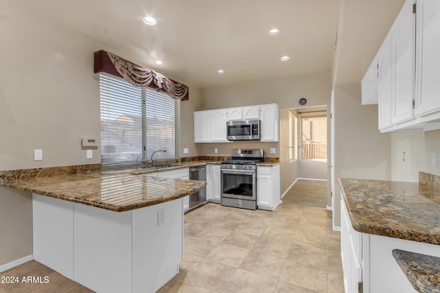 kitchen with white cabinets, sink, dark stone countertops, appliances with stainless steel finishes, and kitchen peninsula