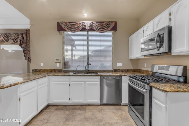 kitchen featuring kitchen peninsula, appliances with stainless steel finishes, sink, dark stone countertops, and white cabinetry