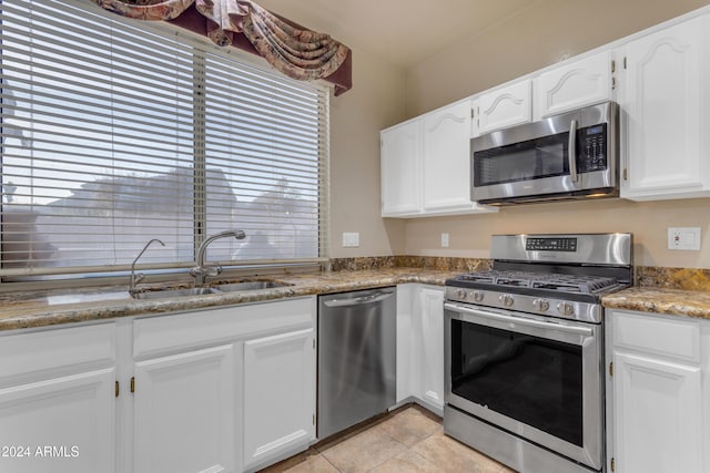 kitchen featuring stainless steel appliances, sink, stone countertops, white cabinetry, and light tile patterned flooring