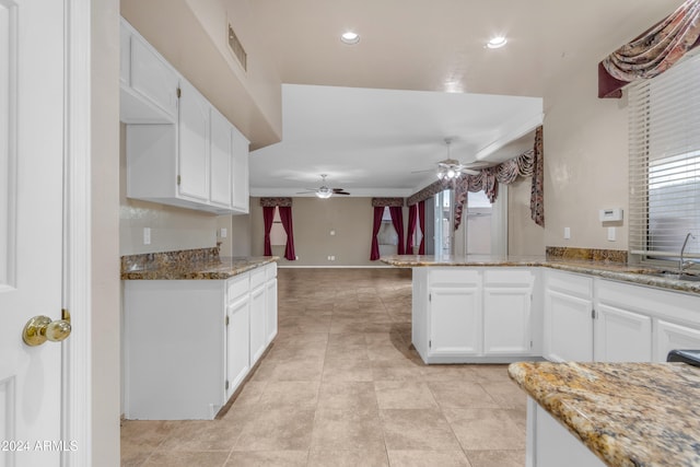 kitchen featuring white cabinets, sink, light stone countertops, light tile patterned floors, and kitchen peninsula