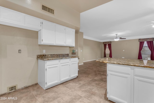 kitchen with dark stone countertops, ceiling fan, and white cabinets