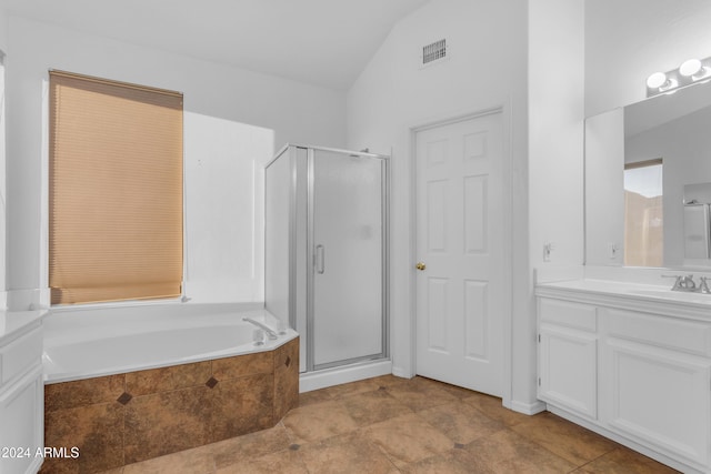 bathroom with tile patterned floors, vanity, separate shower and tub, and vaulted ceiling