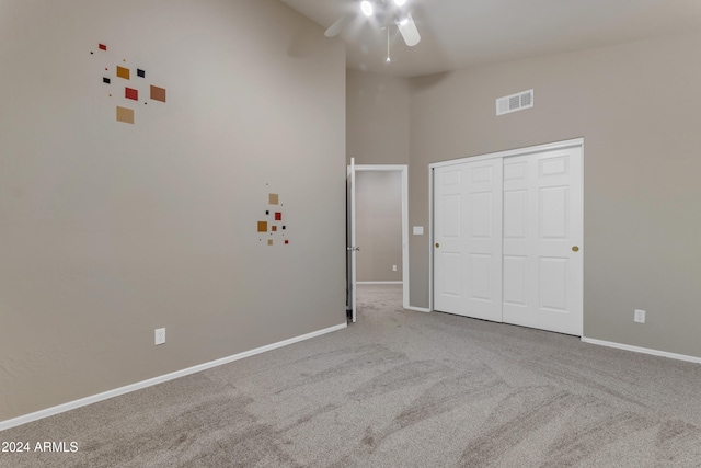 unfurnished bedroom with light carpet, high vaulted ceiling, a closet, and ceiling fan