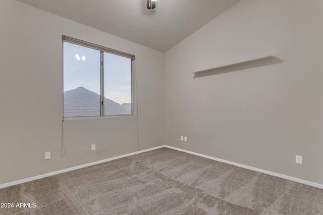 carpeted spare room featuring vaulted ceiling