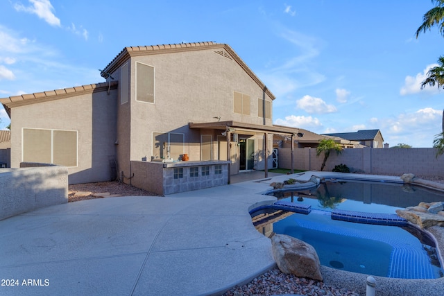 rear view of property with a pool with hot tub and a patio