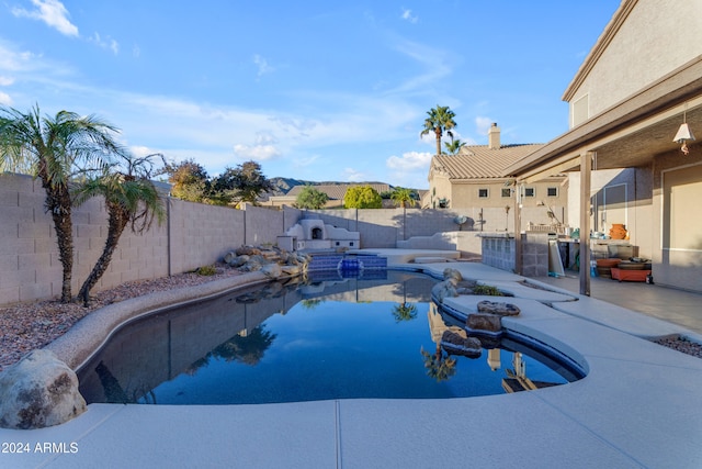 view of swimming pool featuring a jacuzzi, a patio, and exterior kitchen