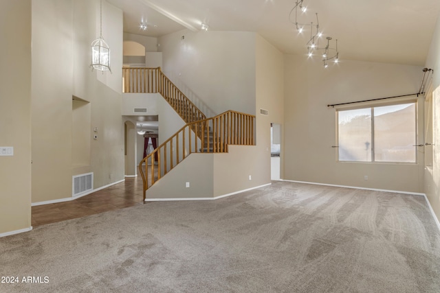 unfurnished living room with carpet flooring and high vaulted ceiling