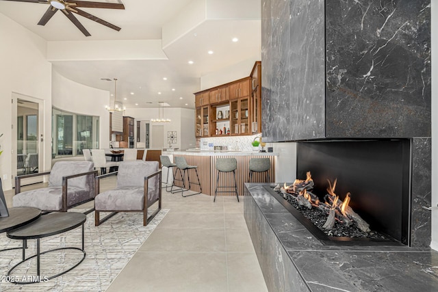 living room with a premium fireplace, ceiling fan, and light tile patterned flooring