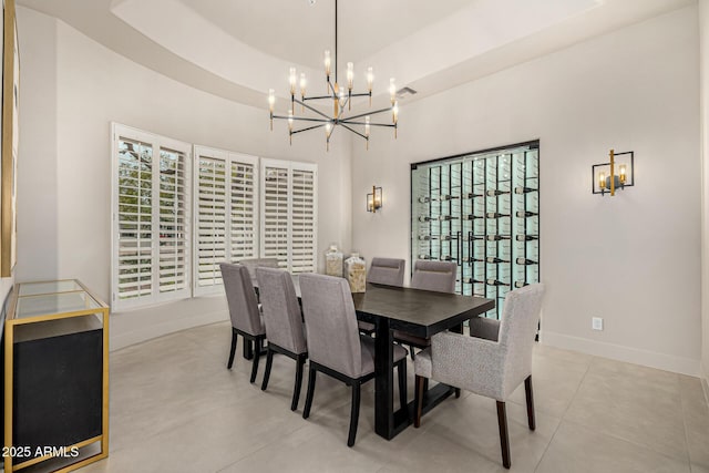 dining area with a raised ceiling, a healthy amount of sunlight, and a notable chandelier