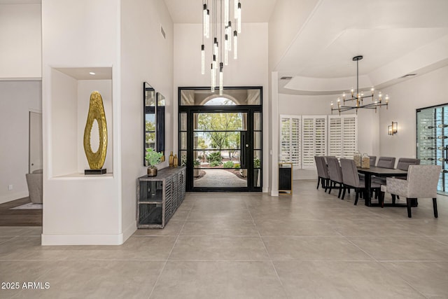 entryway featuring a notable chandelier, a tray ceiling, and a high ceiling