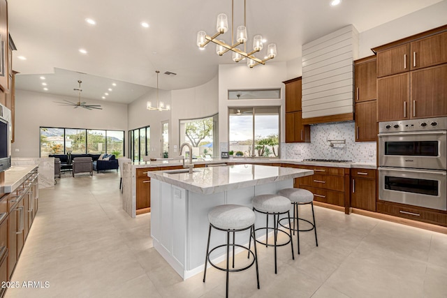 kitchen with hanging light fixtures, stainless steel appliances, a kitchen breakfast bar, and a center island with sink