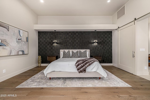 bedroom featuring wood-type flooring and a barn door