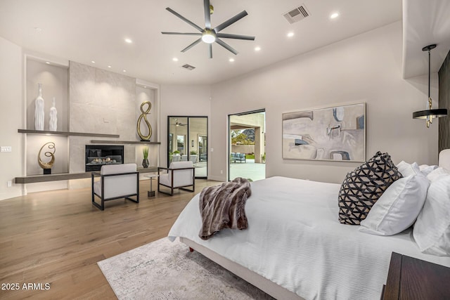 bedroom featuring a tile fireplace and light wood-type flooring