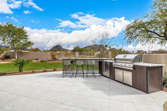 view of patio featuring exterior kitchen, a mountain view, and a grill