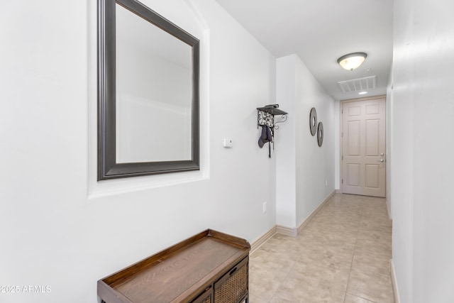 hallway featuring light tile patterned flooring, visible vents, and baseboards